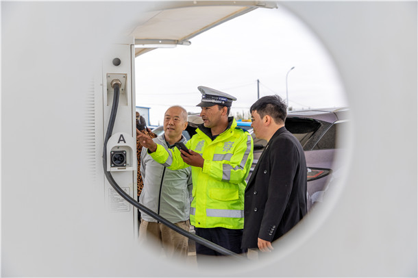 民警向新能源车驾驶人介绍服务区充电桩位置及使用方法。 民警向新能源车驾驶人介绍服务区充电桩位置及使用方法。